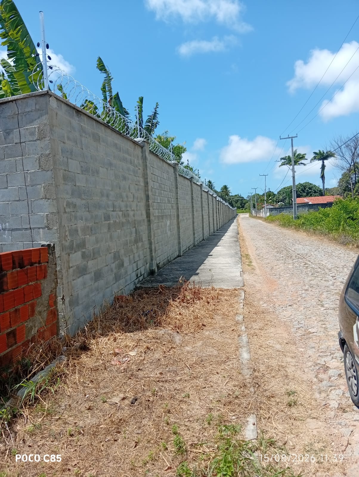 Muro de bloco com trecho em tijolo protegido por concertina, obra de grande extensão